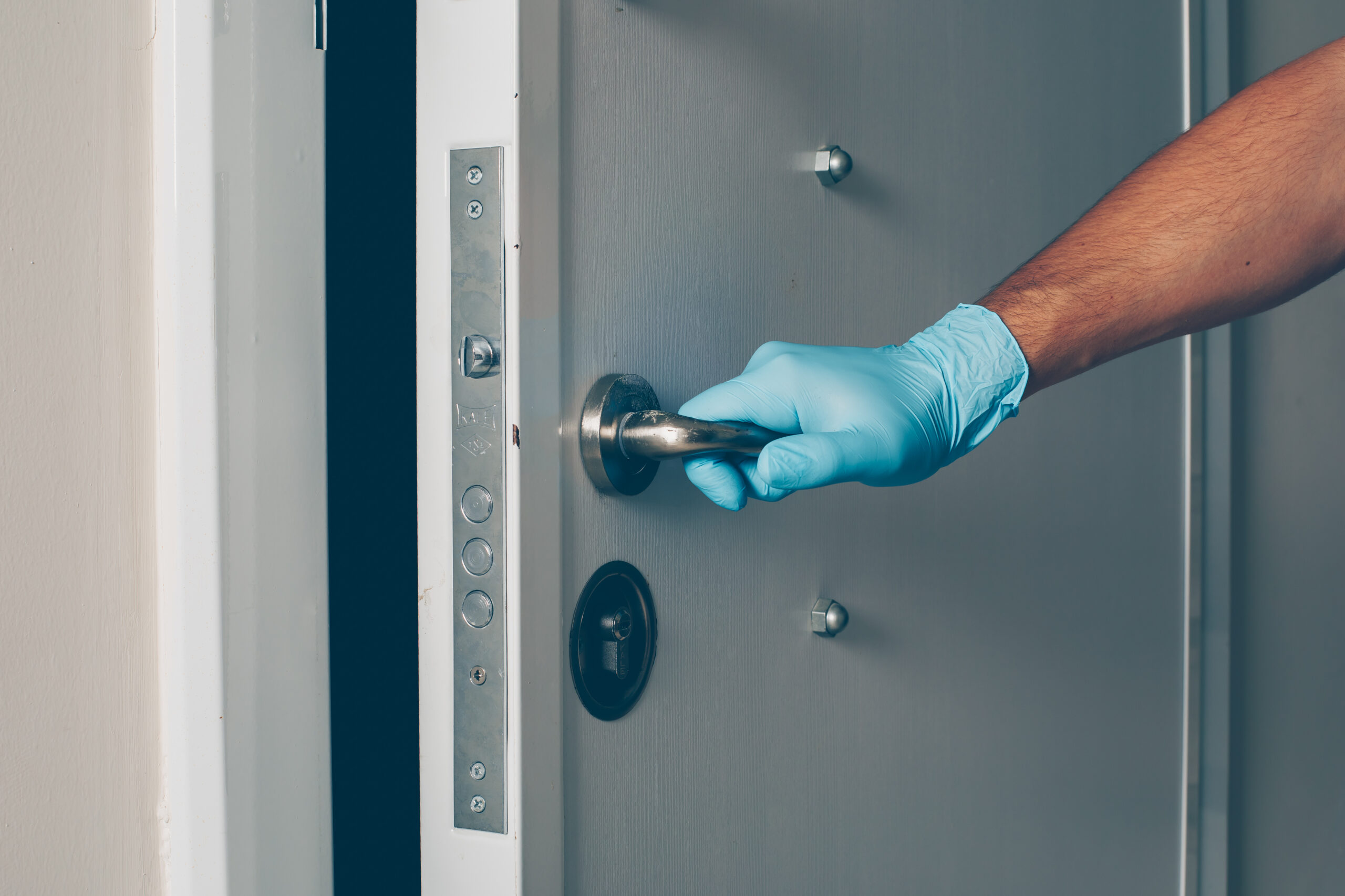 Portrait of a man at room opening the door with hands in gloves coronavirus